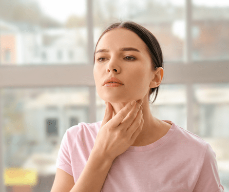 woman holding her neck (essential oil for thyroid nodule)